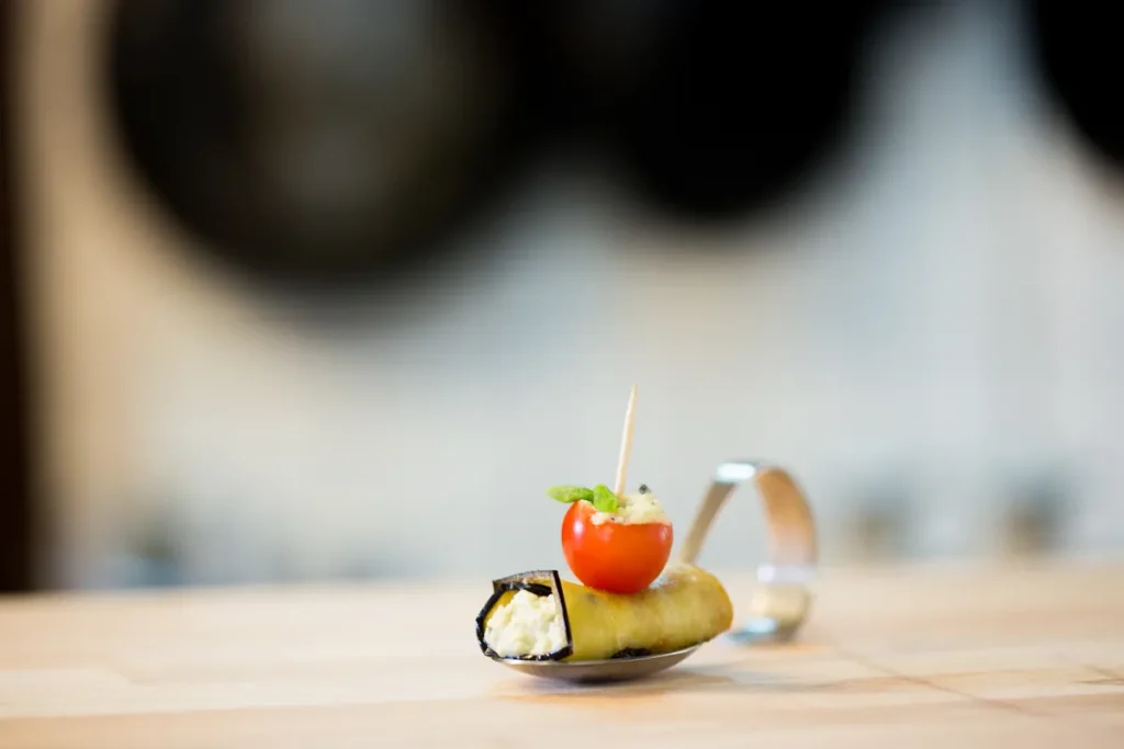 Gefülltes Röllchen mit Cherrytomate als Fingerfood, elegant serviert auf einem Probierlöffel.